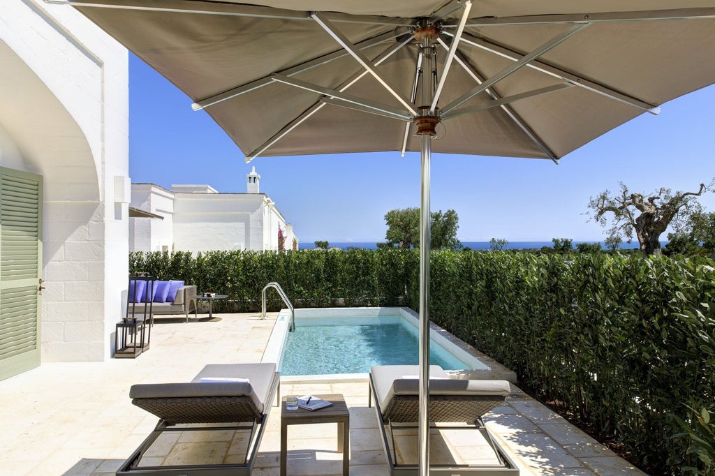 Historic Italian stone masseria with elegant pool terrace surrounded by manicured gardens, olive groves and whitewashed archways