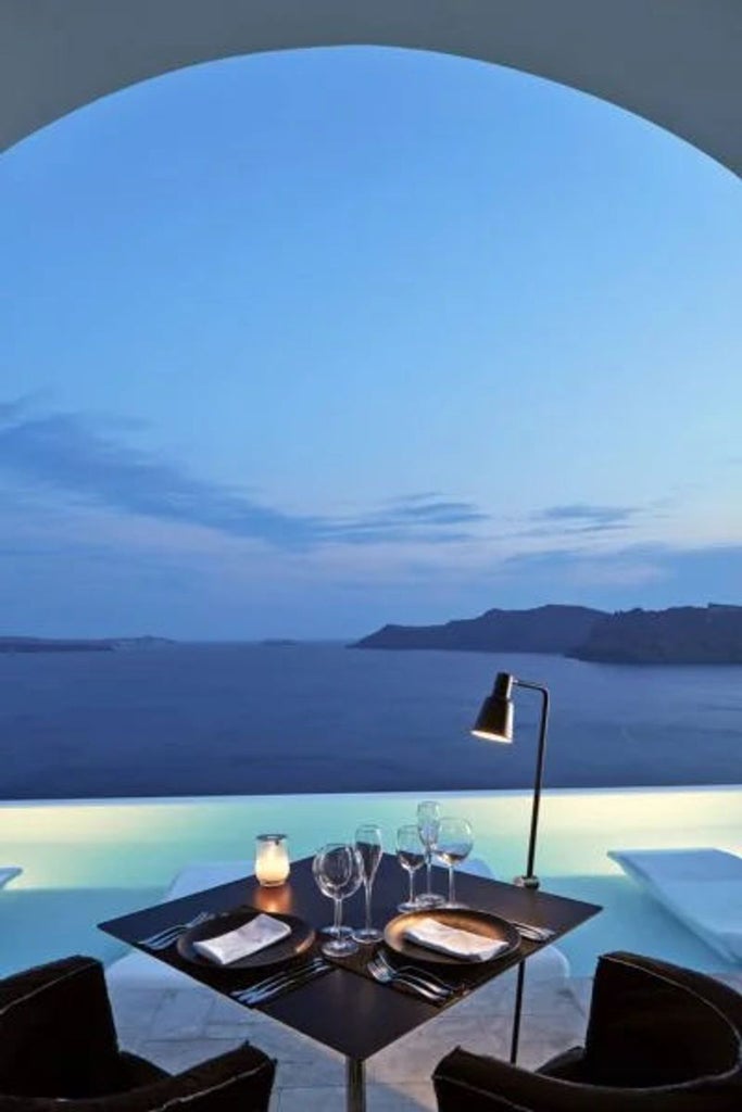 White-washed luxury suite with private infinity pool overlooking Santorini's caldera, featuring curved architecture and sea view terrace