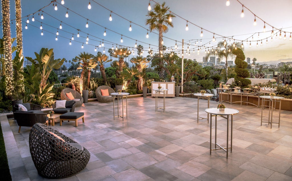 Elegant white Mediterranean-style hotel facade with palm trees, fountain courtyard and luxurious balconies at sunset in Beverly Hills