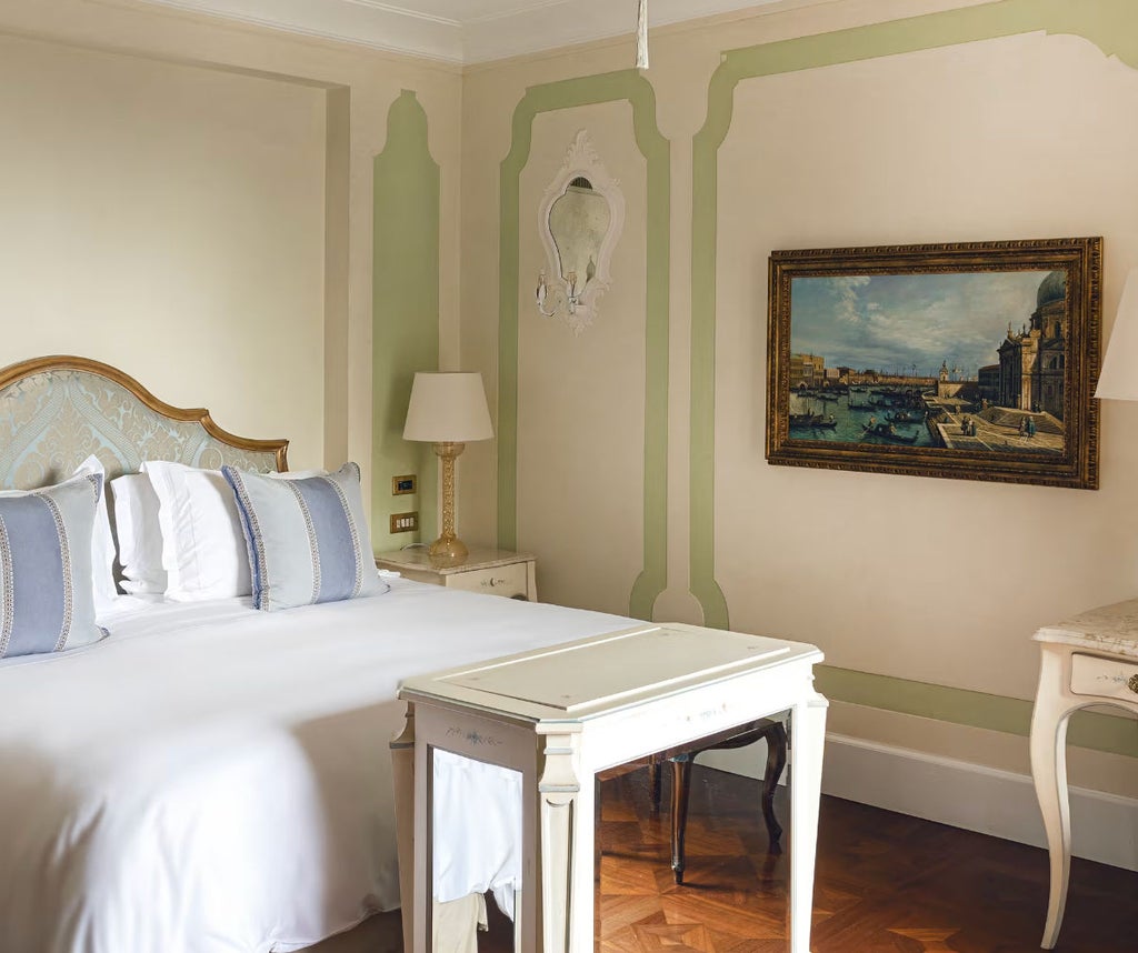 Elegant hotel room with private balcony overlooking Venice lagoon, featuring plush king bed, classic Italian decor and marble accents