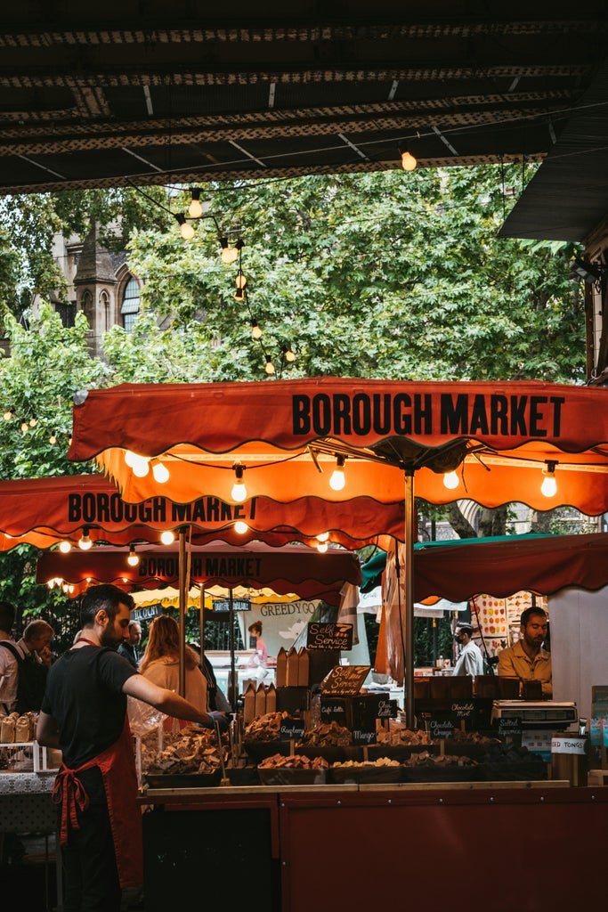 Gourmet food tour through Borough Market's bustling stalls, featuring vibrant produce, artisan cheeses, and local vendors crafting culinary delights mid-afternoon.