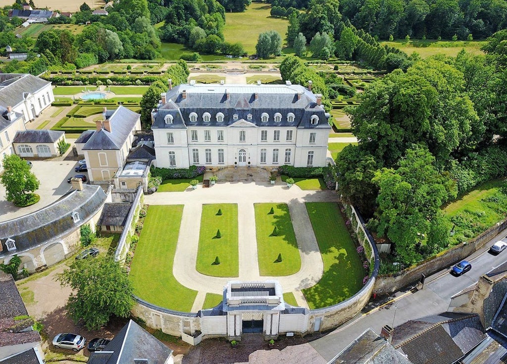 Elegant 18th-century French château hotel with manicured gardens, limestone facade, and grand windows overlooking formal parterre garden