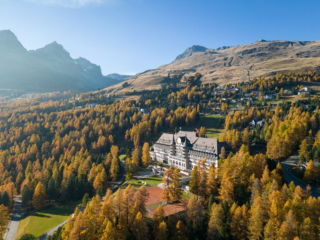 Majestic five-star alpine hotel with ornate tower facades nestled in snowy Swiss mountains, surrounded by pristine evergreen forest