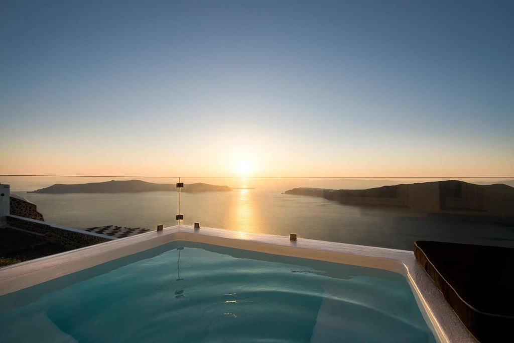 Luxurious Avaton Suite with elegant white interiors, private balcony overlooking the azure Aegean Sea, and minimalist Greek island design elements