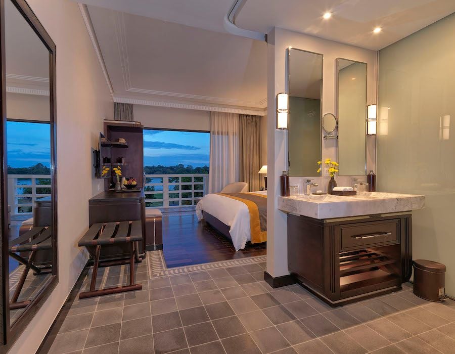 Elegant Superior River View room at Azerai La Residence, featuring colonial-inspired decor, rich wooden furnishings, and panoramic views of the scenic river landscape in Hue, Vietnam