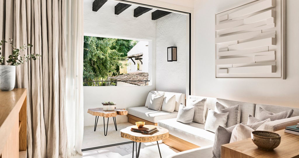 Luxurious Nobu Hotel Marbella deluxe room with modern minimalist design, white linens, sleek furniture, and panoramic view of Mediterranean coastline