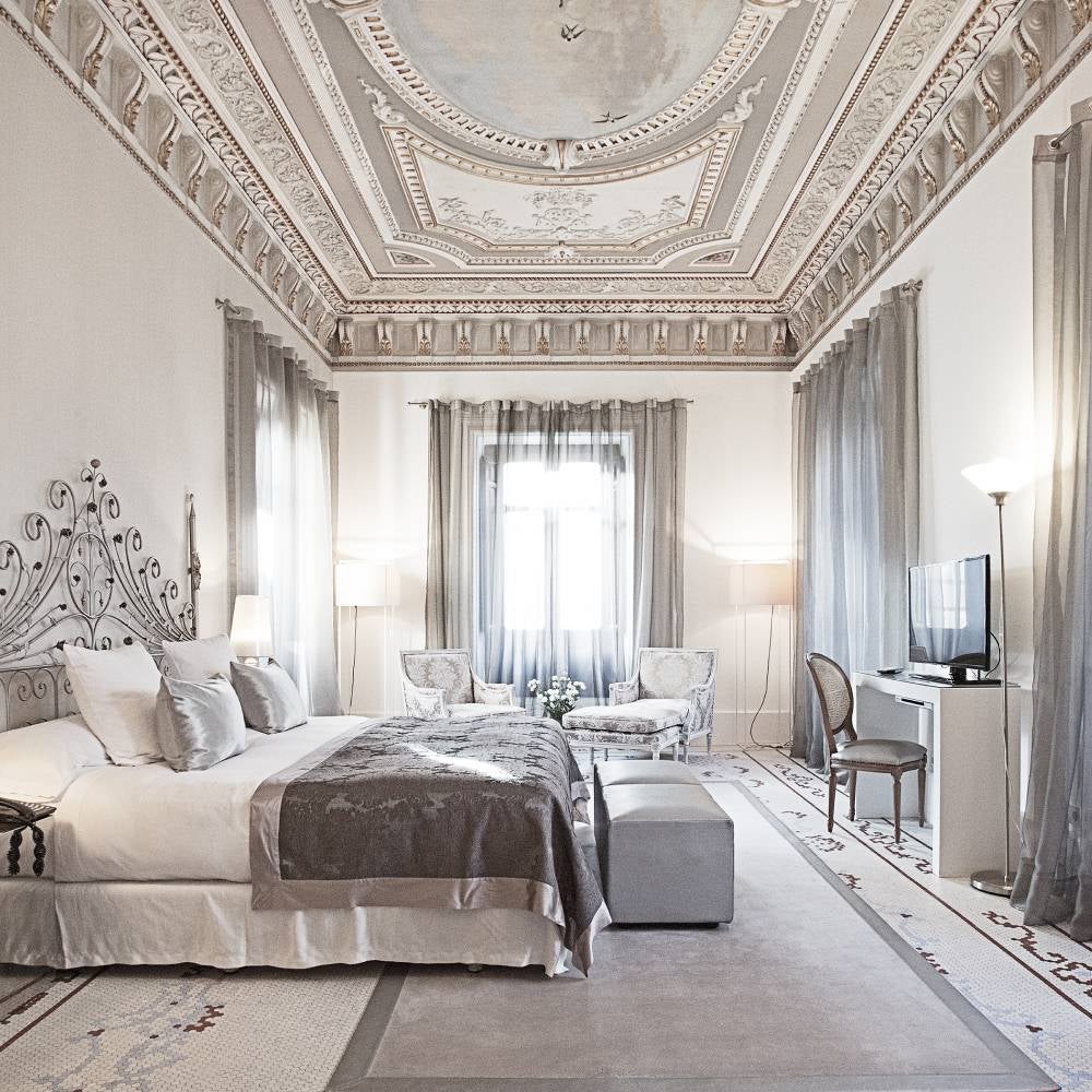 Elegant white 19th-century palace hotel with ornate facade, featuring classic columns, wrought-iron balconies and manicured gardens