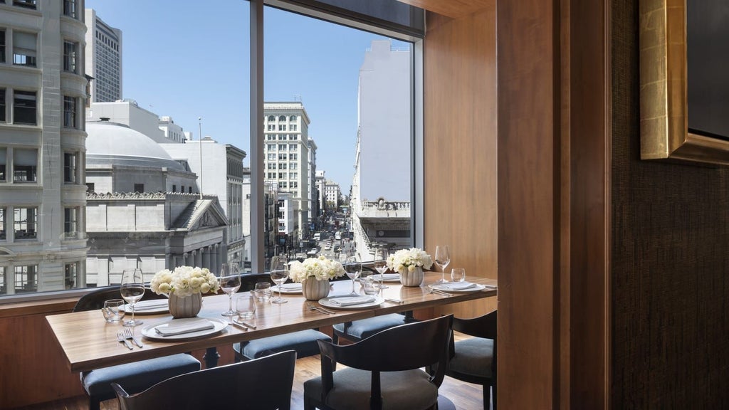 Luxurious glass-fronted hotel tower rising above San Francisco cityscape, showcasing sleek modern architecture with gleaming windows reflecting urban landscape