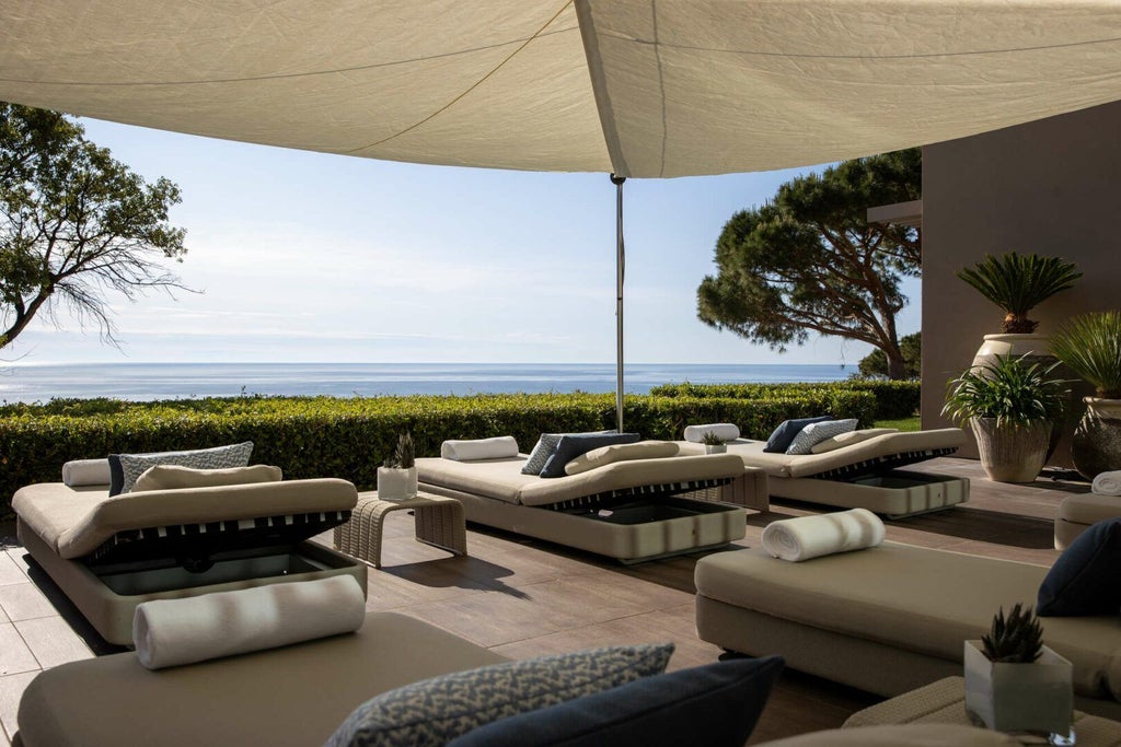 Luxurious infinity pool overlooking azure Mediterranean coastline, nestled in pristine white La Réserve Ramatuelle resort with minimalist design and panoramic sea views