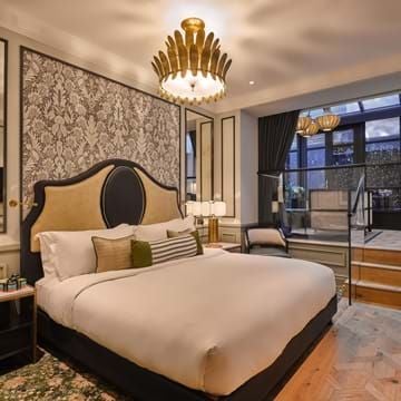 Elegant boutique hotel room with plush emerald green velvet headboard, sophisticated neutral color palette, and refined dark wood furnishings at The scenset Townhouse