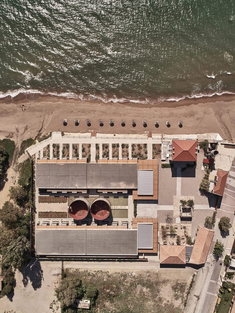 Luxurious seaside hotel in Greece with minimalist concrete design, nestled between olive groves and azure Ionian Sea, featuring clean lines and natural textures