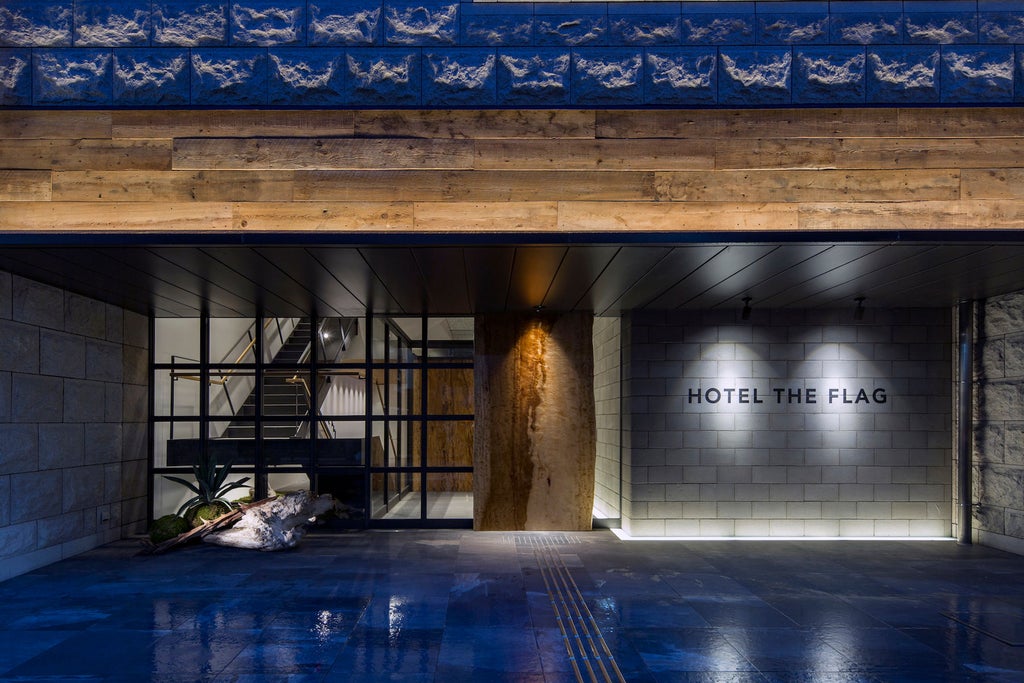 Modern Japanese hotel exterior with sleek glass facade, illuminated signage, and geometric architecture in an upscale urban setting at dusk