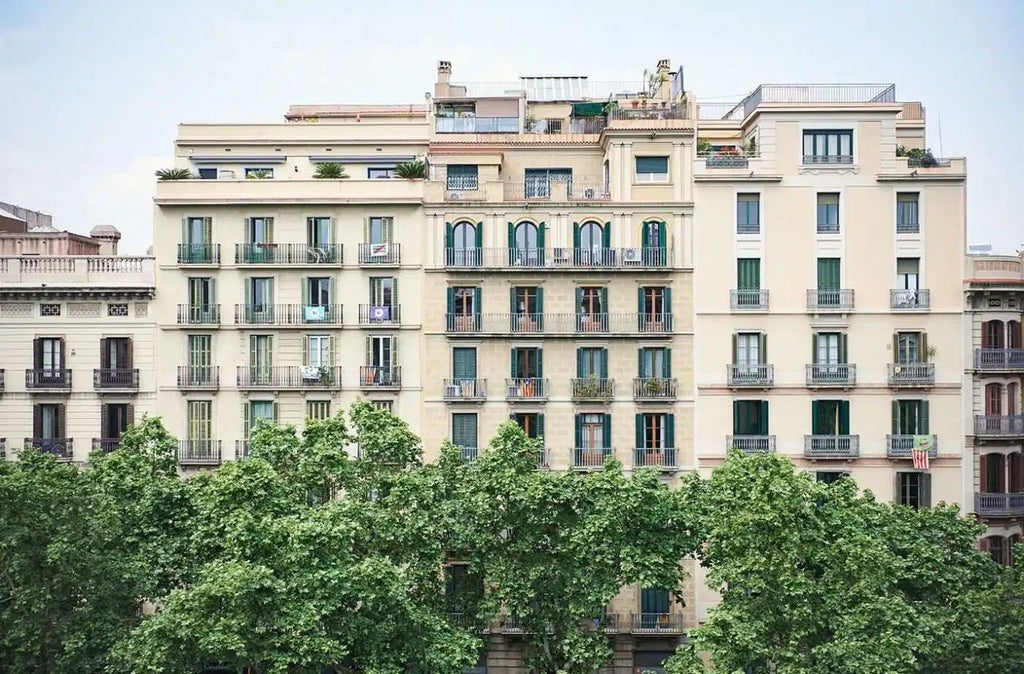 Chic minimalist hotel room with natural light, wooden floors, white walls, mid-century modern furnishings, and Barcelona's architectural elegance