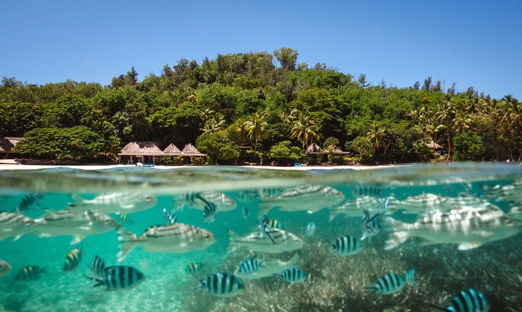 Spacious Fijian beachfront villa with elegant wooden floors, panoramic ocean views, king-sized bed, and modern tropical design elements in soft neutral tones.