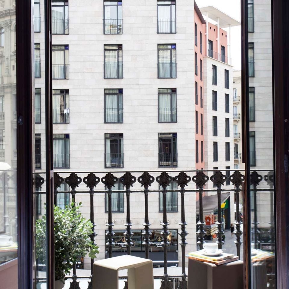 Spacious Barcelona hotel room with modern minimalist design, crisp white linens, sleek wooden furniture, and warm natural lighting streaming through large windows