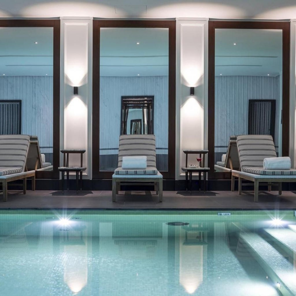 Elegant Parisian hotel interior with chic white furniture, ornate mirror, and soft lighting showcasing luxurious French design and sophistication.