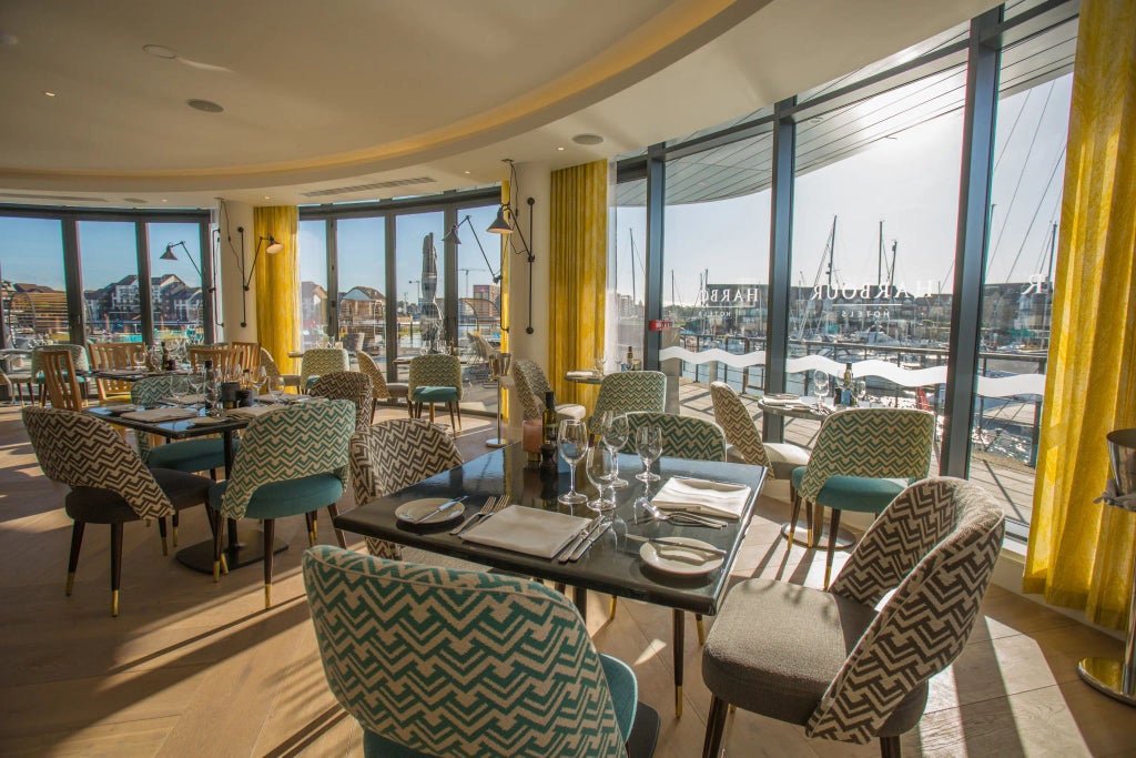 Elegant waterfront hotel with modern glass facade overlooking Southampton's harbor, illuminated at dusk with sleek architectural design and maritime charm