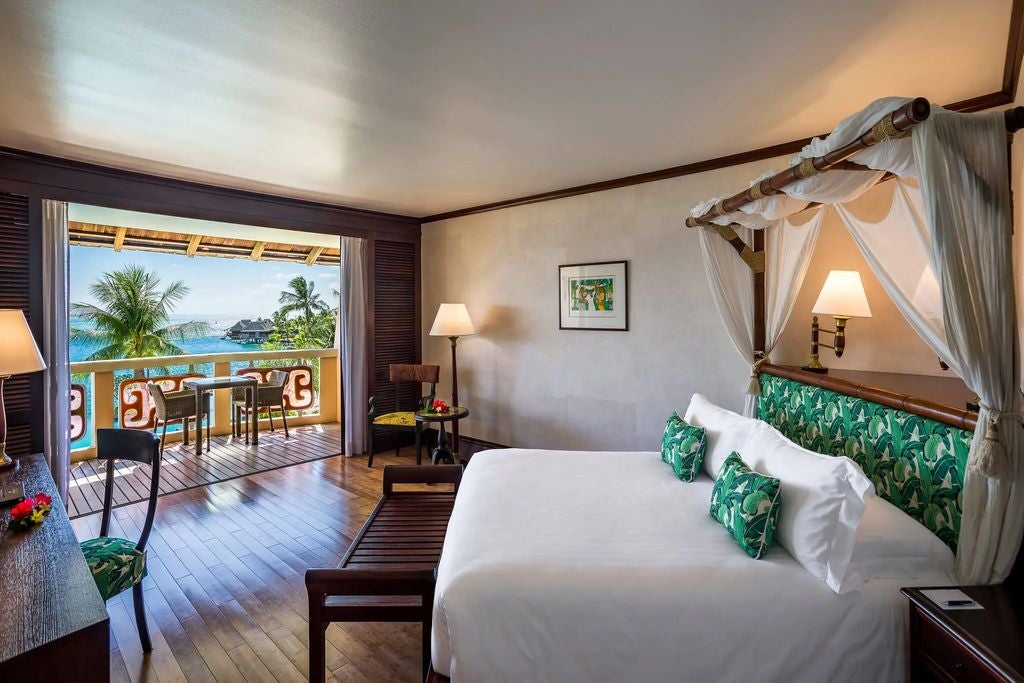 Luxurious suite with modern furnishings, floor-to-ceiling windows, private balcony overlooking Moorea Island and turquoise lagoon waters