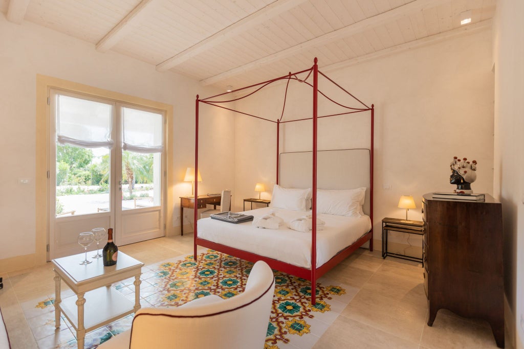 Elegant Sicilian boutique hotel room with soft neutral tones, antique wooden furnishings, and delicate lace curtains overlooking lush Mediterranean gardens