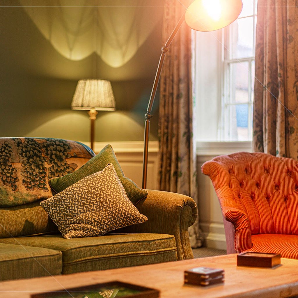 Elegant deluxe suite at The Talbot Malton, featuring plush king bed, classic British decor, rich wooden furnishings, and pristine white linens with sophisticated ambiance