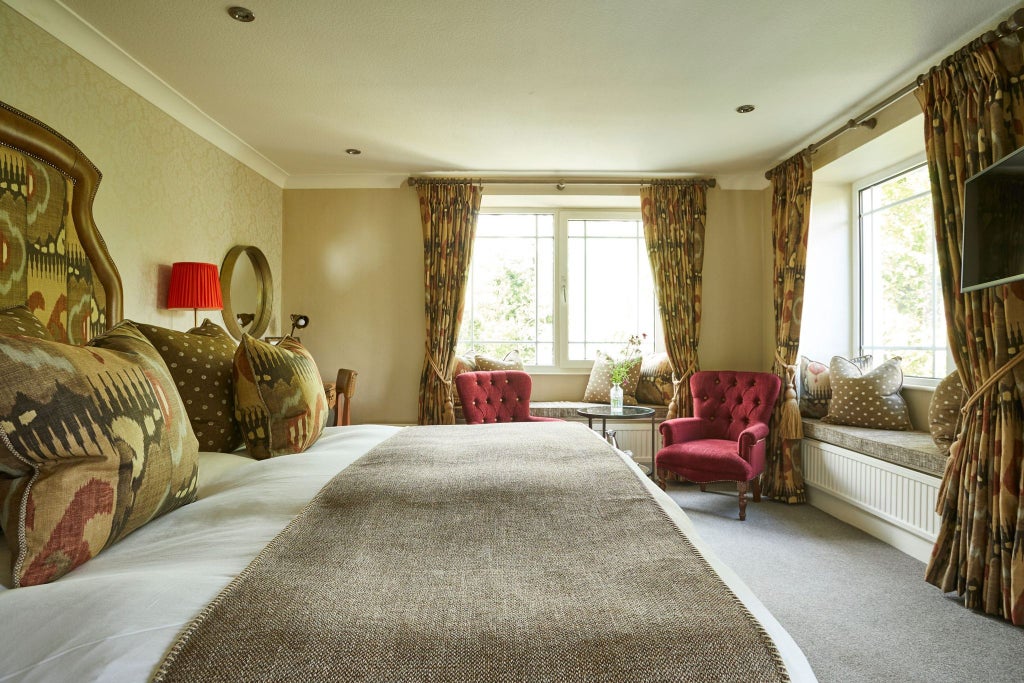 Elegant classic plus room at Rothay Manor Hotel, featuring plush bedding, refined wooden furniture, and soft neutral color palette with countryside view