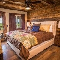 Rustic lodge room with wooden furnishings, king bed, large windows overlooking scenic mountain landscape near scenset National Park in southwestern United States