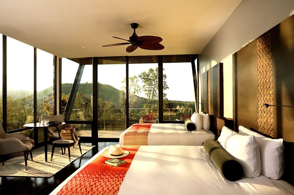 Luxurious Pikaia Lodge terrace room with panoramic Galapagos landscape, featuring modern decor, expansive windows, and natural wood furnishings.