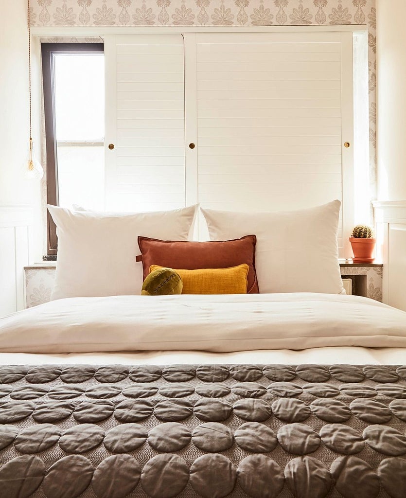 Cozy modern hotel room with minimalist design, featuring white walls, wooden flooring, crisp white bedding, and sleek urban aesthetic in German hotel