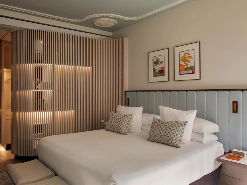 Elegant superior room at Grand Hotel Central, featuring plush white bedding, modern Spanish decor, and floor-to-ceiling windows overlooking Barcelona's cityscape