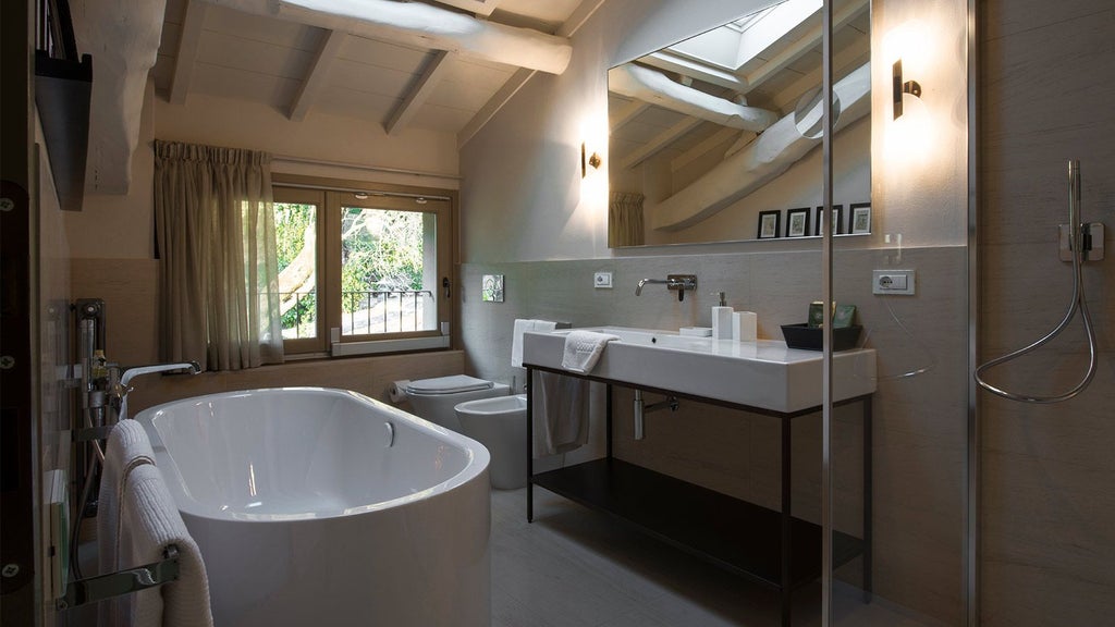 Elegant minimalist bedroom at Locanda al Colle with white linens, soft natural light, wooden floors, and a serene Tuscan countryside view