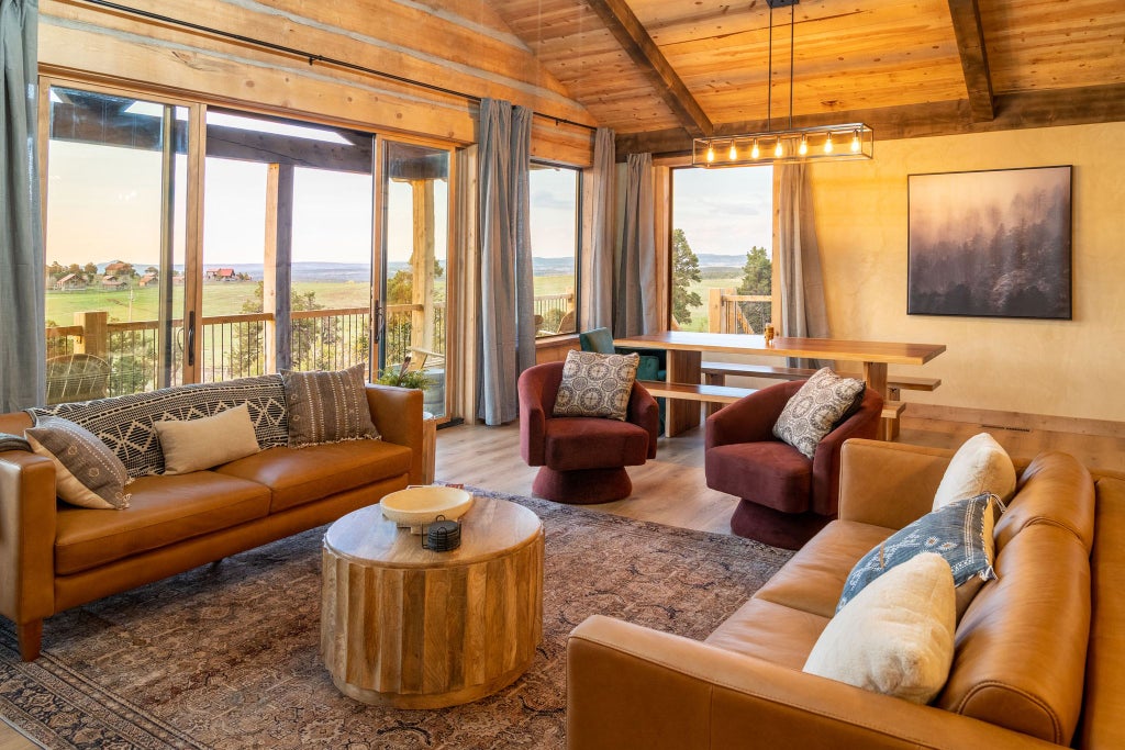 Rustic lodge bedroom with wooden furnishings, plush bedding, and panoramic mountain views at a scenic ranch accommodation near a national park