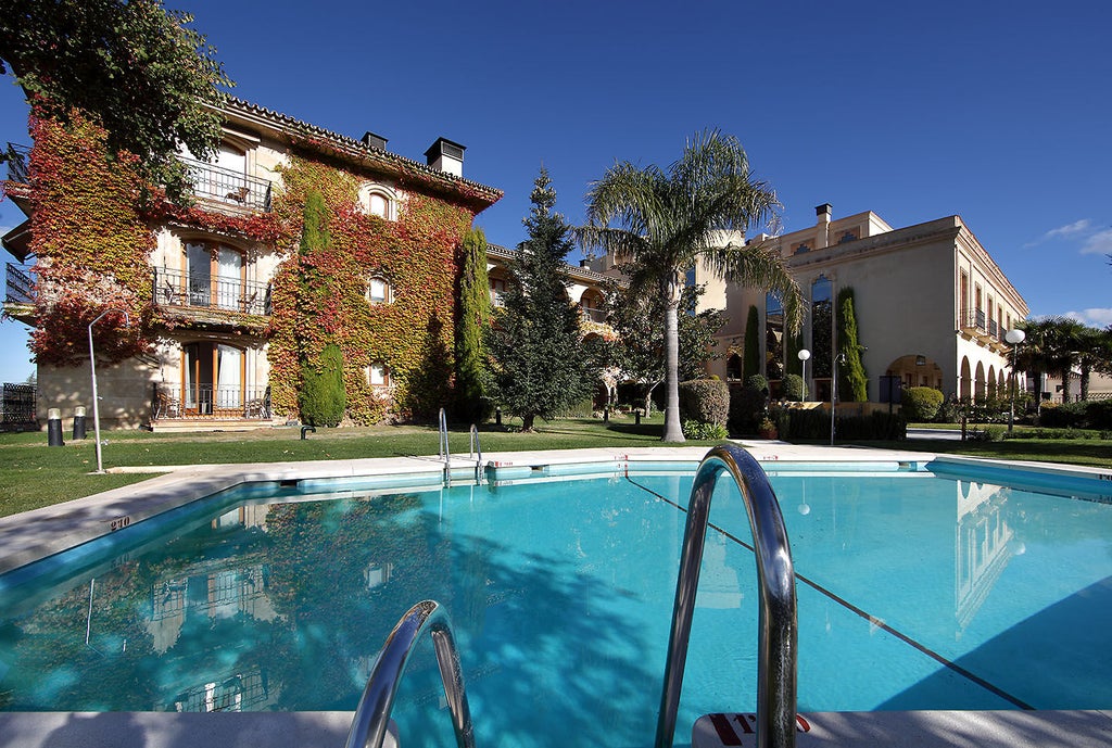 Spanish luxury hotel El Parador featuring a stone facade with arched windows, ornate balconies, and flowering gardens against mountain backdrop