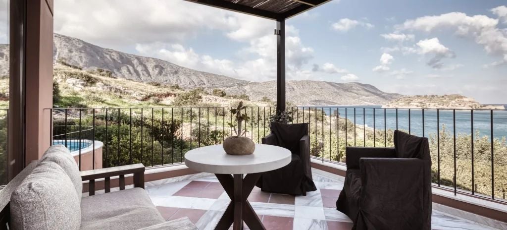 Luxurious family suite with private outdoor jacuzzi, overlooking blue Aegean waters and white-washed Domes of Elounda resort architecture in scenic Greece