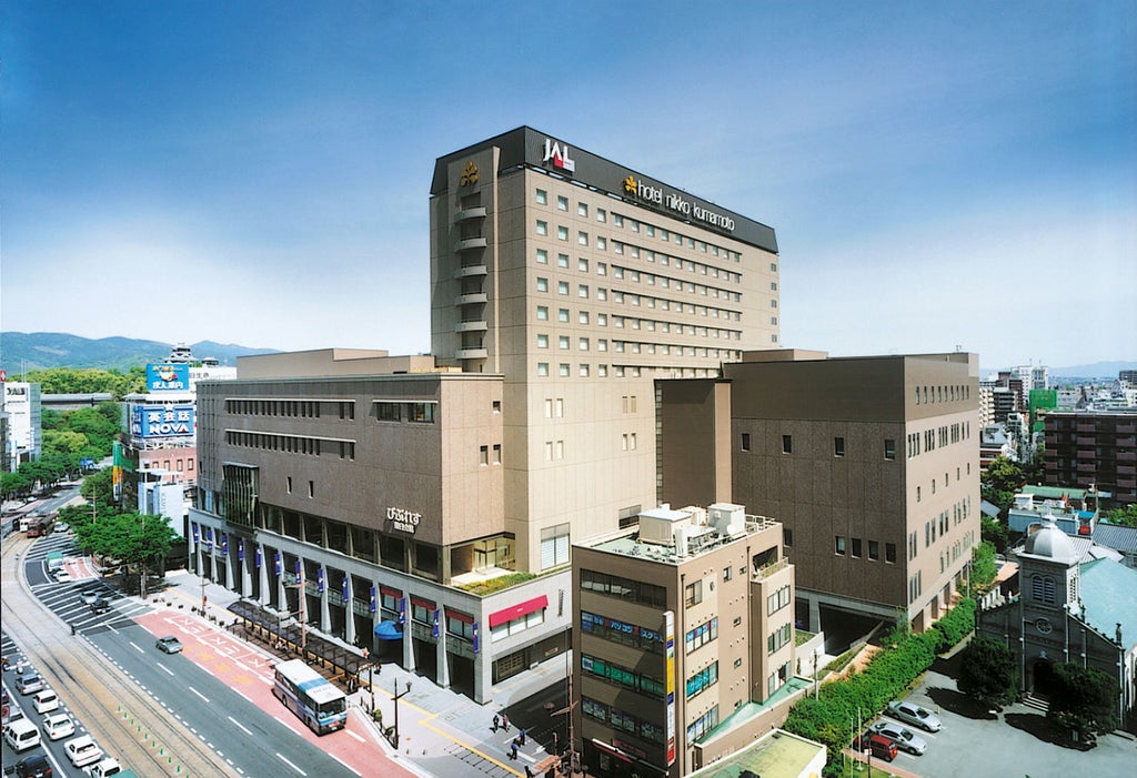 Modern hotel tower with sleek glass facade in downtown Kumamoto, featuring upscale architectural design and illuminated entrance canopy