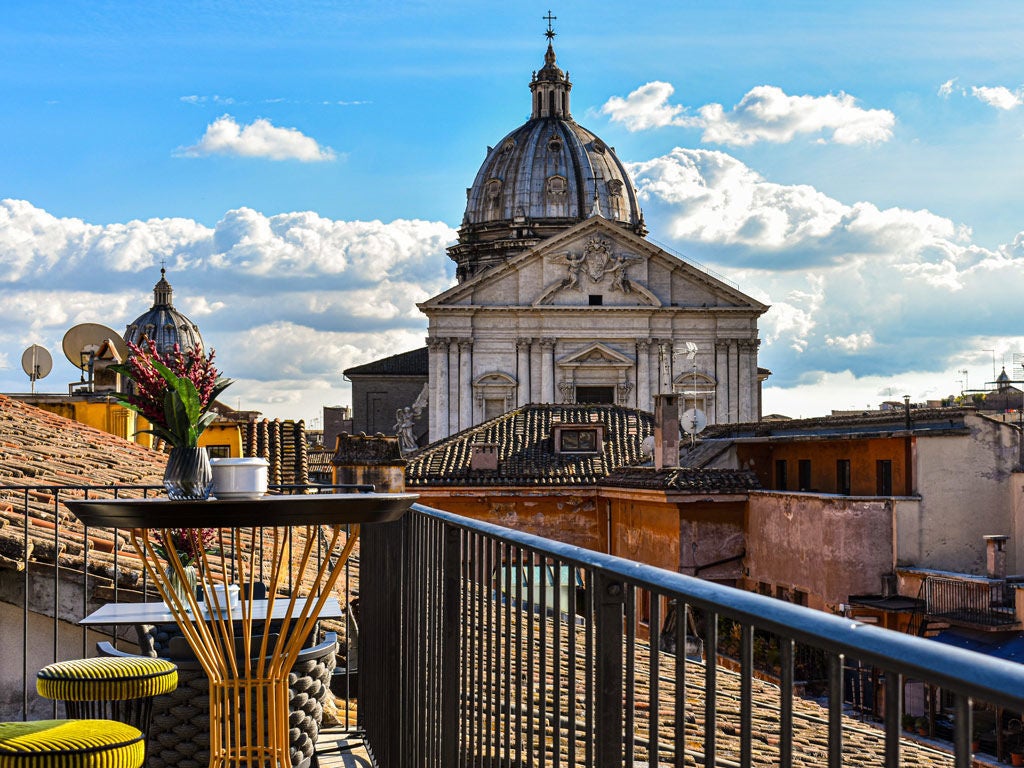 Elegant boutique hotel exterior in Rome with classic Italian architecture, ornate balconies, and warm evening lighting illuminating beige facade