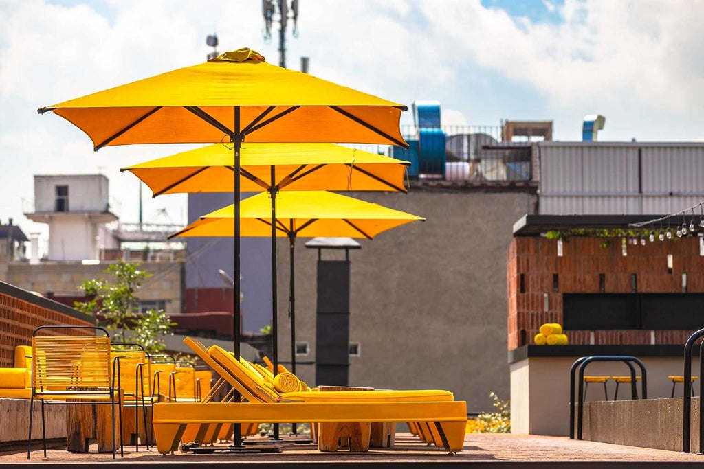 Luxurious rooftop terrace of Downtown Mexico hotel with dramatic city skyline, colonial architecture, and elegant outdoor seating at sunset