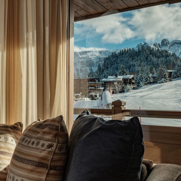 Luxurious alpine ski lodge room with panoramic mountain views, contemporary wooden furnishings, and cozy fireplace at Portetta Hotel in French ski resort