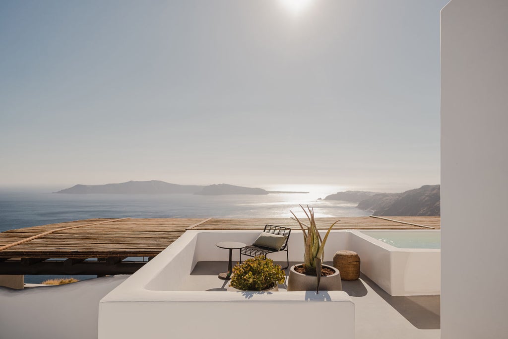 Minimalist luxury suite with infinity pool overlooking Santorini's caldera, featuring white curved architecture and panoramic sea views