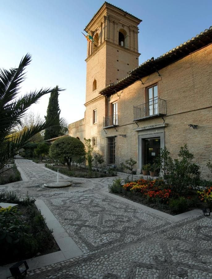 Historic Parador Granada hotel with elegant stone archways and columns, nestled within Alhambra palace complex at sunset