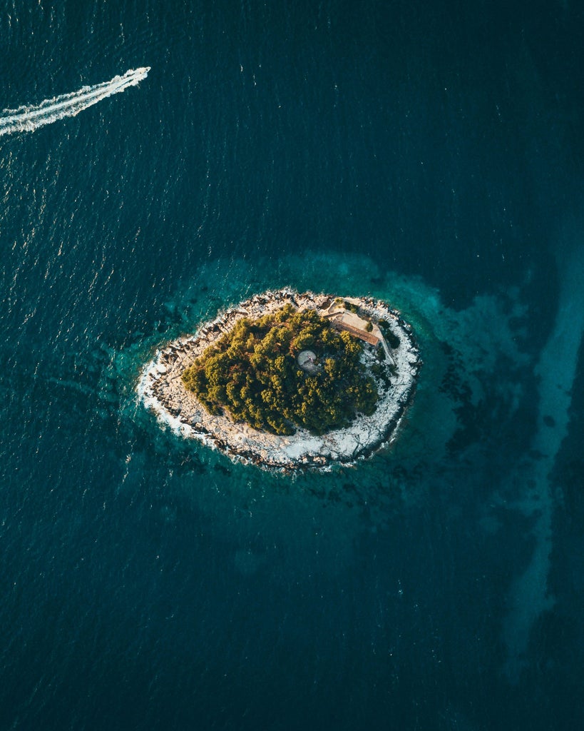 Luxurious white speedboat cruising past Pakleni Islands' emerald coves, with Hvar's medieval town visible in the backdrop