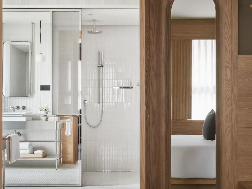 Modern hotel room with floor-to-ceiling windows, minimalist furnishings, king bed with crisp white linens, and city views of Taipei's Da An district