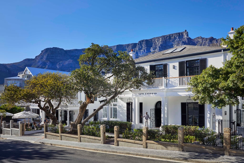 Elegant colonial-style villa with white columns and black railings, featuring manicured gardens and Cape Dutch architecture in Cape Town