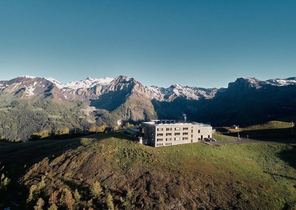 Luxurious alpine hotel room with panoramic mountain views, minimalist wooden design, and floor-to-ceiling windows overlooking Swiss mountain landscape