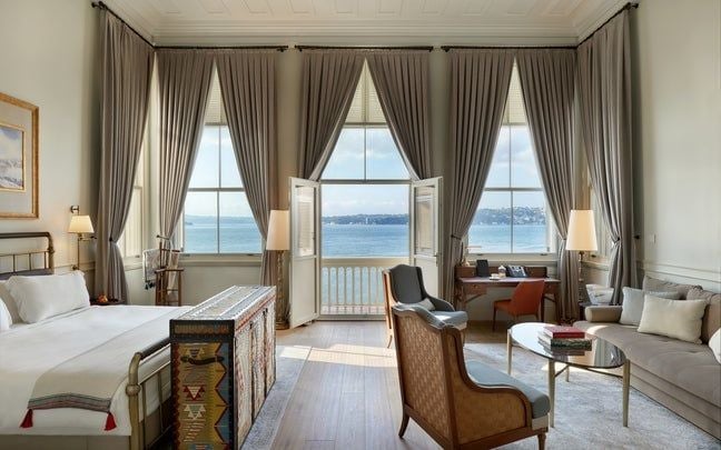 Luxurious Bosphorus Junior Suite with elegant balcony overlooking Istanbul's scenic waterway, featuring sophisticated Turkish decor and modern amenities.