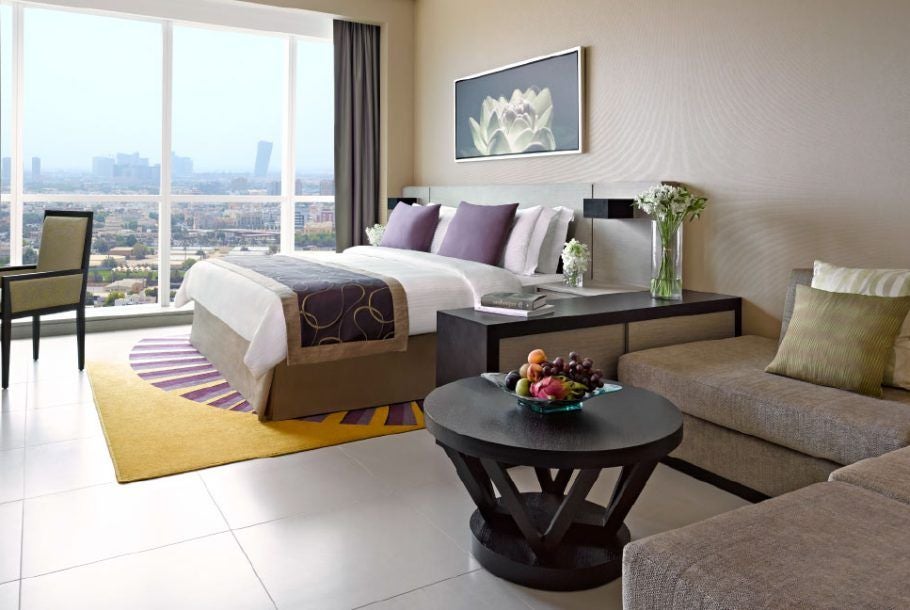 Spacious modern studio apartment at scenset hotel with plush king bed, sleek marble bathroom, city skyline view, and contemporary UAE luxury design elements