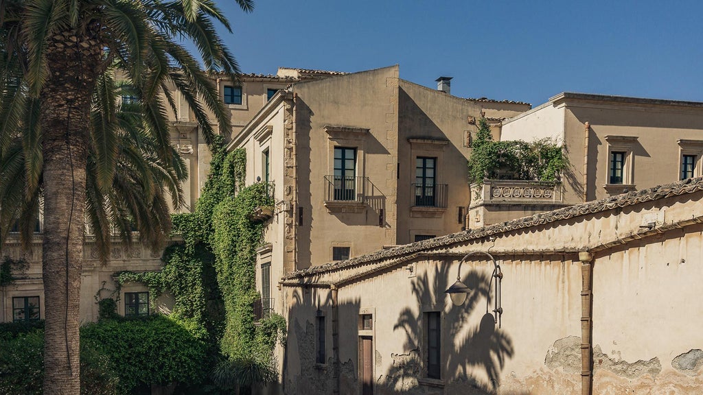 Luxurious historic Sicilian hotel with elegant stone facade, lush balconies, and warm Mediterranean light illuminating traditional architectural details