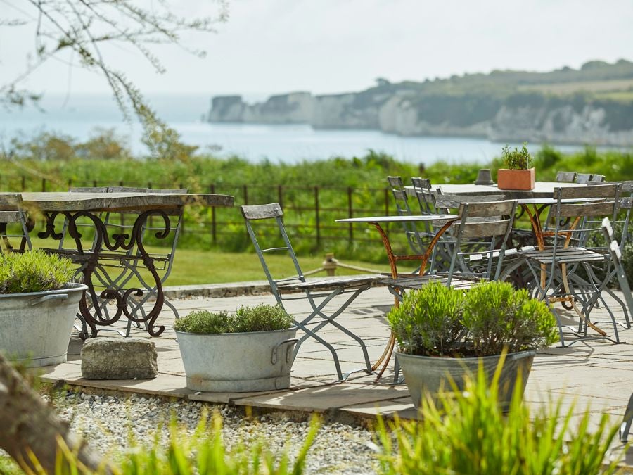 Rustic-chic luxury hotel nestled in rolling South Downs landscape, featuring elegant stone exterior with lush green gardens and countryside views.