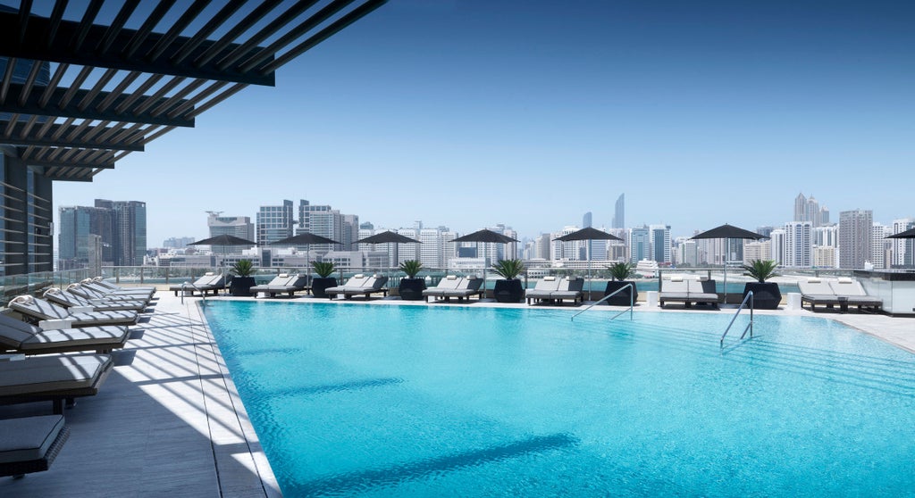 Modern luxury hotel rising above Al Maryah Island waterfront with glass facade, infinity pool, and sunset-lit Arabian Gulf views