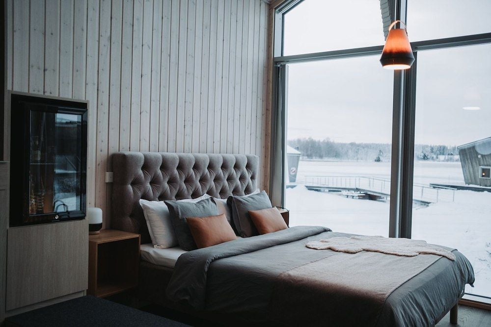 Minimalist Nordic wooden cabin interior with rustic log walls, cozy family sleeping area, modern design blending natural textures and warm neutral tones at Arctic Bath resort