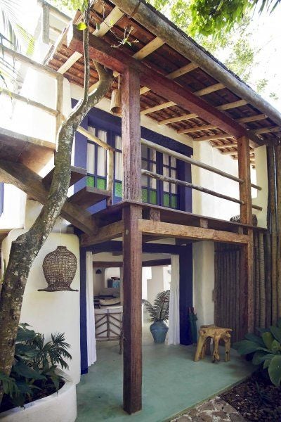 Luxurious wooden terrace overlooking lush Brazilian treetops, featuring minimalist design with rustic wooden furniture and an infinity pool at UXUA Casa Hotel and Spa